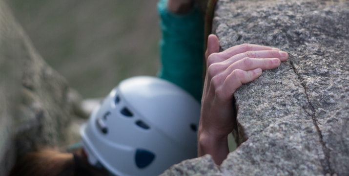 Close-up of a climber’s fingers gripping a granite ledge on a rock climb