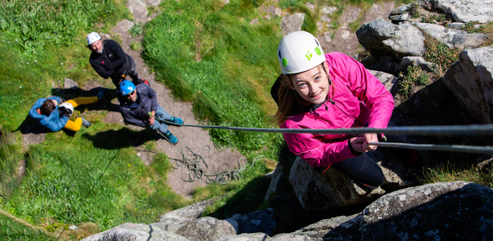 Young climber smiling as she tops out on a beginner top rope route in Cornwall