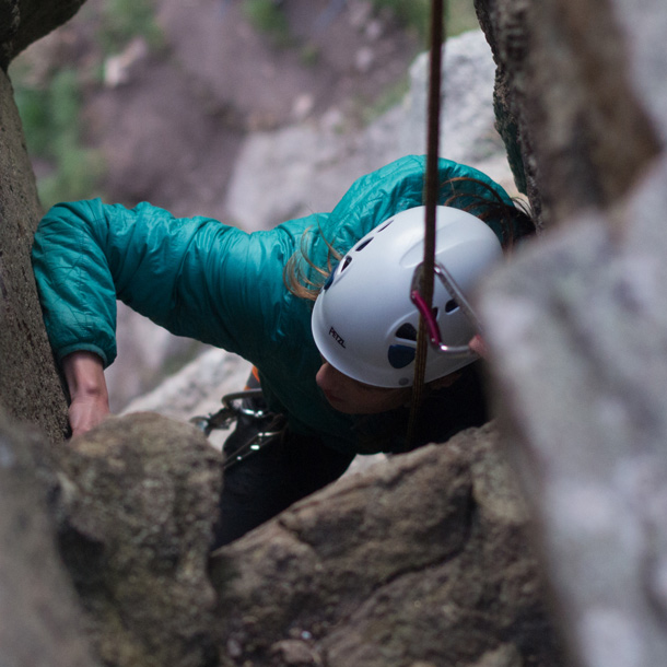 Climber navigating a narrow granite chimney on a coastal crag in Cornwall
