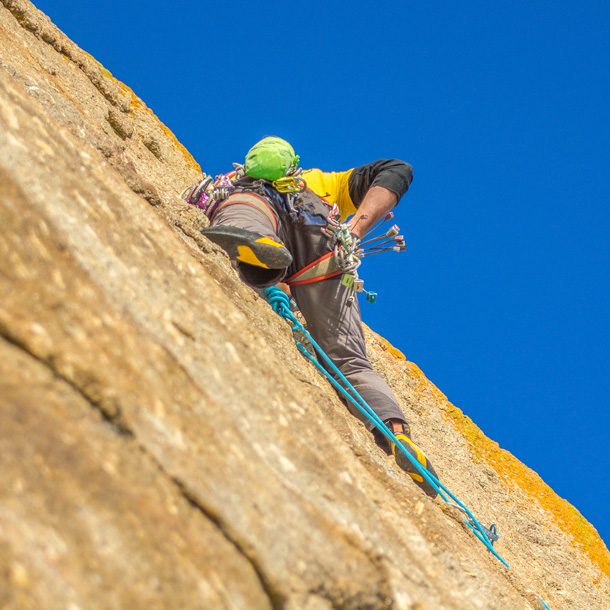 Climber leading a multi-pitch route in Cornwall, focusing on technique and protection placement.