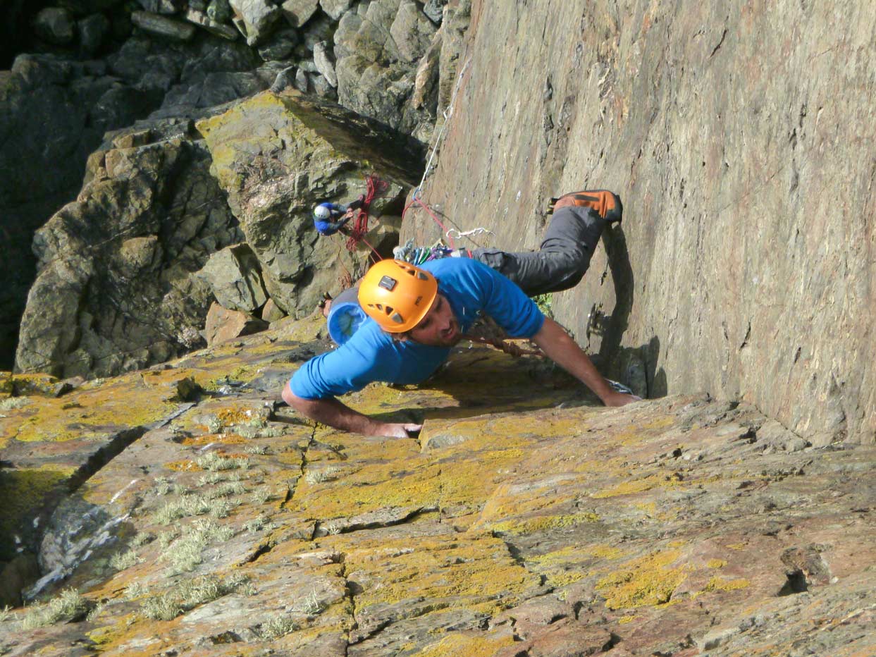 Climber on an E1 sea cliff route at Kenidjack, classic sea cliff climbing in Cornwall.