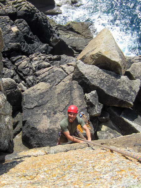 Climber seconding a granite sea cliff route at Sennen — a hands-on way to learn what is trad climbing.