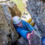 Boy stretching for the anchor chains on a chimney climb in Cornwall