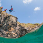 Person coasteering and cliff jumping into the sea at Praa Sands in west Cornwall – one of the best things to do in St Ives Cornwall
