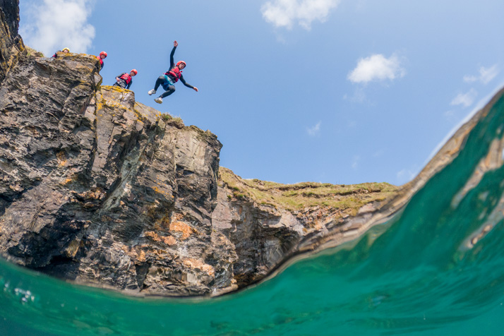 Person coasteering and cliff jumping into the sea at Praa Sands in west Cornwall – one of the best things to do in St Ives Cornwall