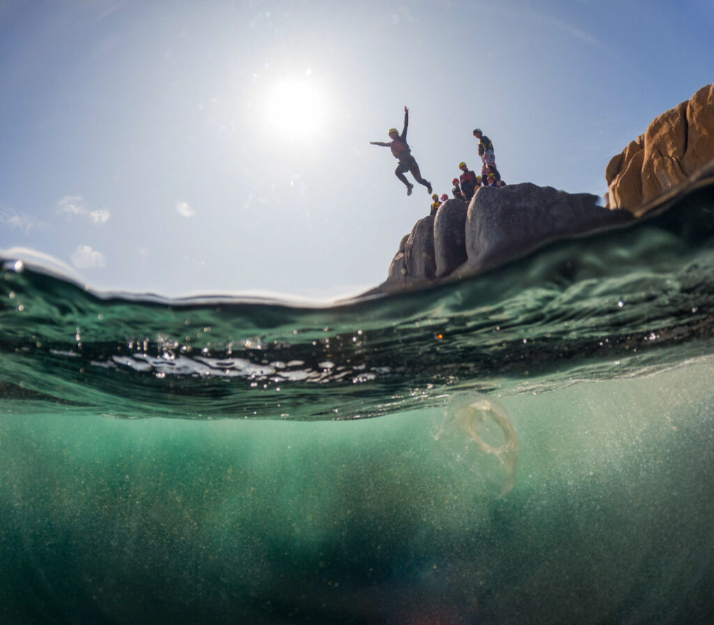 Coasteering cliff jump at Peninnis Head, Isles of Scilly, with a moon jellyfish below the surface