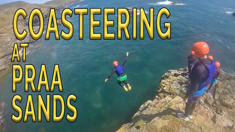 Person jumping from a rocky ledge during a guided coasteering session at Praa Sands, Cornwall