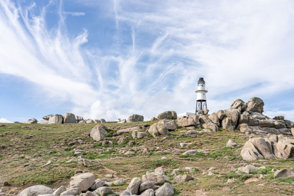 Peninnis Head Lighthouse on the Isles of Scilly with thrift in bloom and whispy sky