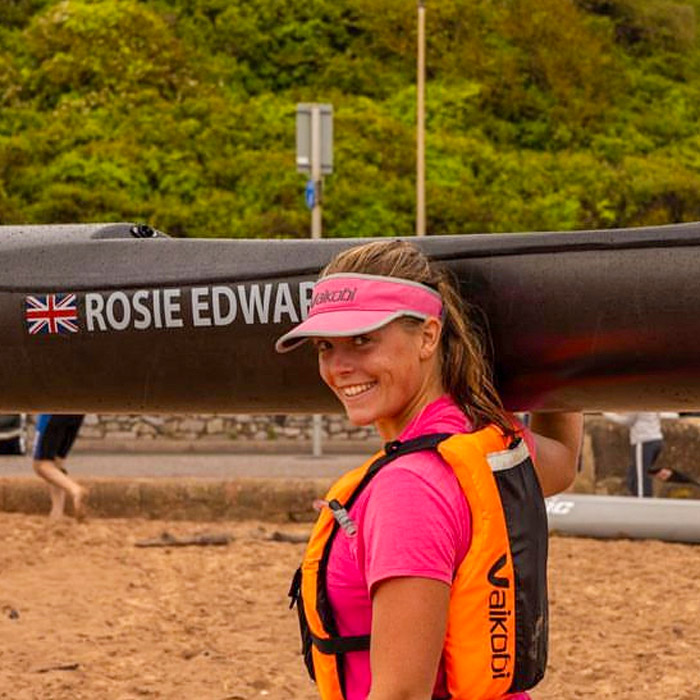Rosie Edwards smiling beside a surf ski at a surf lifesaving competition.